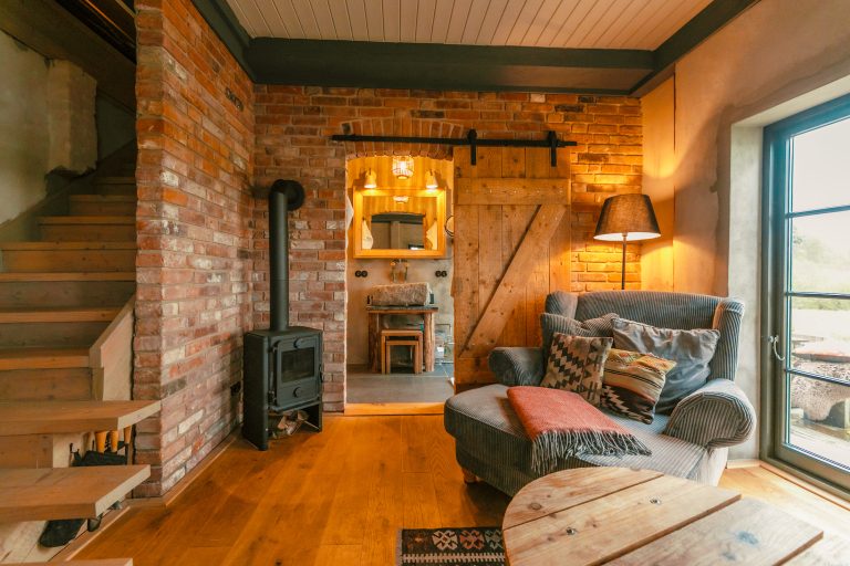 Cabin River: Living space with brick wall, wood-burning stove and armchair, Hof Bissee