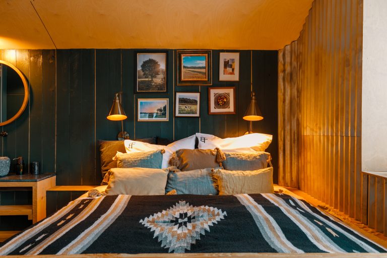 Cabin No.1: Double bed with patterned wool blanket in front of a green picture wall, Hof Bissee