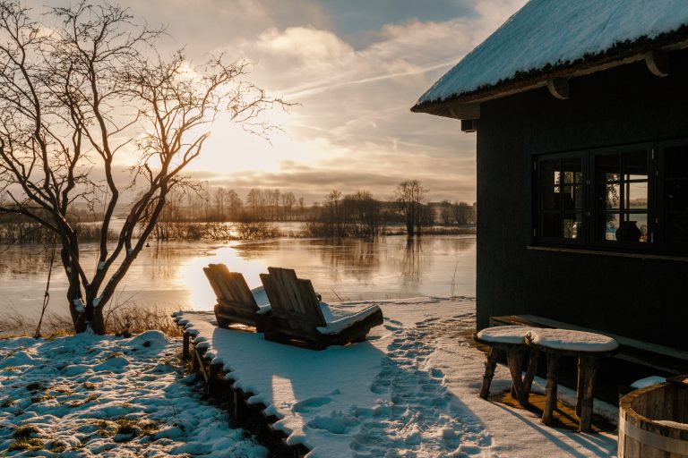 Cabin Forrest: Snow-covered terrace with sun loungers by the water at sunrise, Hof Bissee