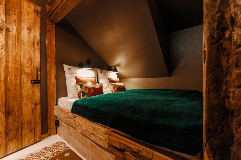 Cabin No.4: Wooden bed with green bedspread under the sloping ceiling, Hof Bissee