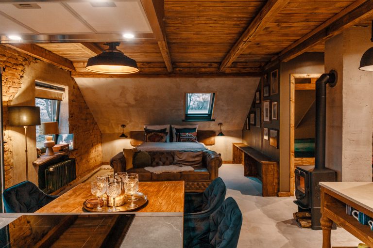 Cabin No.4: Living and dining area under wooden beams with wood-burning stove, Hof Bissee