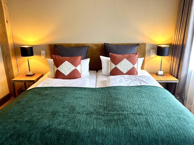 Room No.1: Double bed with green bedspread and patterned cushions, Hof Bissee