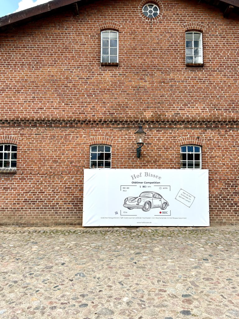 Banner for veteranbilkonkurrencen foran murstensbygningen, Hof Bissee