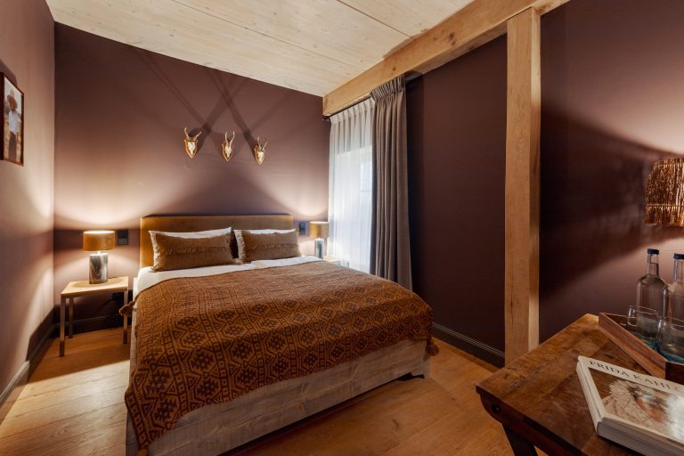 Room No.3: Double bed with antler decoration on the dark red wall, Hof Bissee