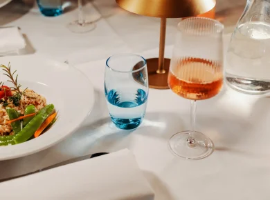 Risotto, water glass and rosé on a white tablecloth in the restaurant, Hof Bissee