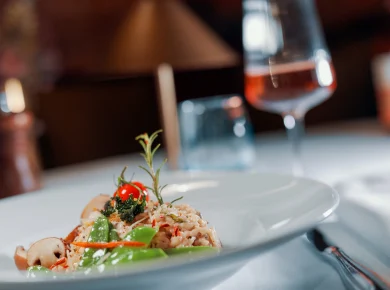 Risotto with sugar snap peas and mushrooms, behind it a glass of rosé, Hof Bissee