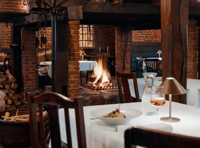 Dining room with open fireplace and laid tables in the restaurant, Hof Bissee